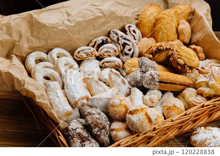 Delicious assortment of fresh pastries and cookies in a rustic basket, dusted with powdered sugar 120228838