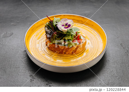 Artistic gourmet toast with fresh greens and edible flower on a vibrant yellow plate Artistic gourmet toast with fresh greens and edible flower on a vibrant yellow plate 120228844