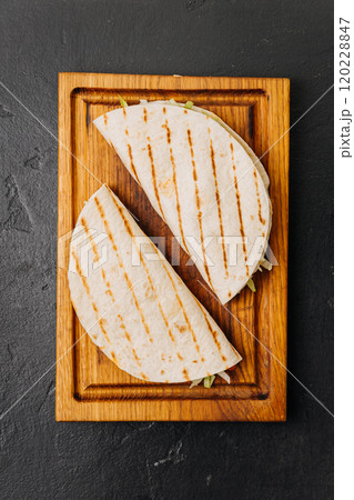 Grilled tortilla wraps with fresh veggies on a wooden board for a quick and tasty meal Grilled tortilla wraps with fresh veggies on a wooden board for a quick and tasty meal 120228847