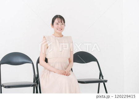 パイプ椅子に座る20代女性 120229415