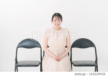 パイプ椅子に座る20代女性 120229416