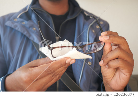 cleaning eyeglass with tissue close up  120230377