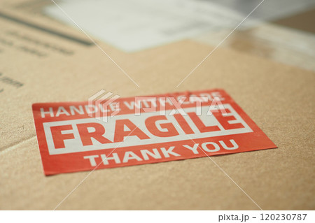 A cardboard box marked with a caution label for fragile goods handling during shipping 120230787
