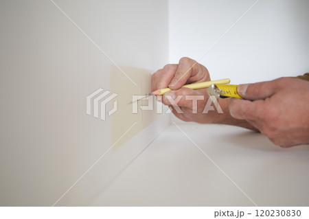 Man measuring wall with a tape measure Man measuring wall with a tape measure 120230830