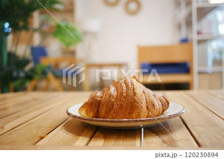 A Freshly Baked Croissant is beautifully presented on a rustic Wooden Table, ready to enjoy 120230894