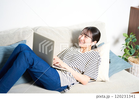 ソファーに寝そべる私服の若い女性 リビング スマホ ソファーに寝そべる私服の若い女性 リビング スマホ 120231341