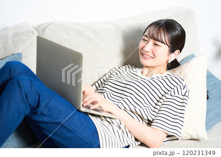 ソファーに寝そべる私服の若い女性 リビング スマホ ソファーに寝そべる私服の若い女性 リビング スマホ 120231349