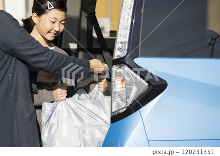 スーパーの駐車場お母さんと一緒に荷物を入れる子供 お手伝いイメージ スーパーの駐車場お母さんと一緒に荷物を入れる子供 お手伝いイメージ 120231351