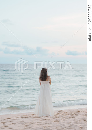Happy traveler woman in white dress enjoy beautiful sea view, young woman standing on sand and looking ocean at tropical beach. Freedom, relaxing, vacation holiday and summer travel concept 120231720