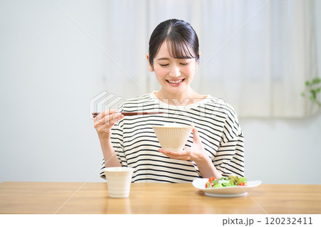 お米を食べる若い女性 120232411