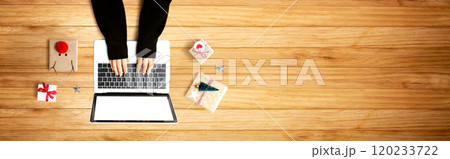 Person using a laptop computer with Christmas gift boxes 120233722