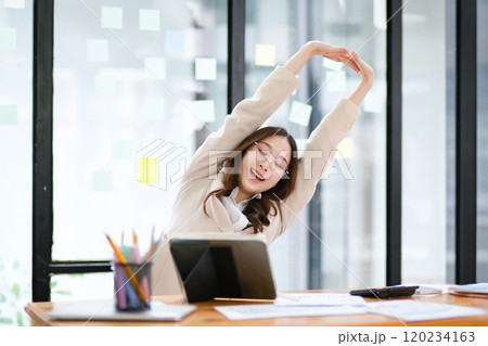 Businesswoman stretching at her desk during a break in the office 120234163