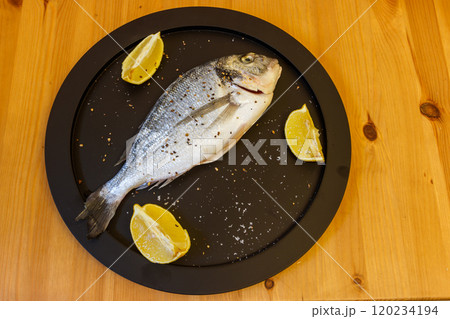 Raw fresh fish dorado with lemon and spices on wooden table. Top view Raw fresh fish dorado with lemon and spices on wooden table. Top view 120234194