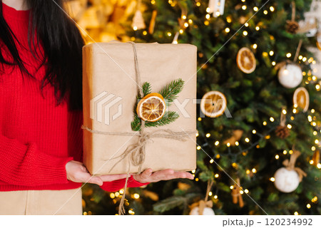 Woman is holding a brown box with a green leaf and orange slices with ribbon tied around it Woman is holding a brown box with a green leaf and orange slices with ribbon tied around it 120234992