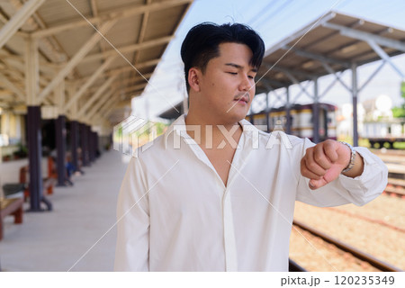 Portrait of Handsome Young Asian Man Outdoors Waiting For Train 120235349
