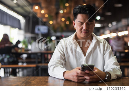 Portrait of Handsome Young Asian Man Sitting in Coffee Shop Restaurant Portrait of Handsome Young Asian Man Sitting in Coffee Shop Restaurant 120235362
