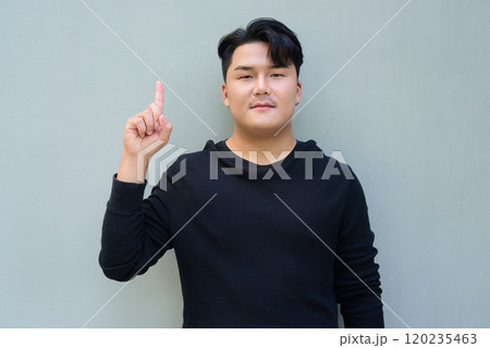 Portrait of Handsome Young Asian Man Against Plain Background Outdoors Portrait of Handsome Young Asian Man Against Plain Background Outdoors 120235463