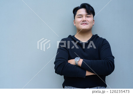 Portrait of Handsome Young Asian Man Against Plain Background Outdoors 120235473