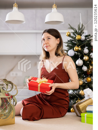 Cheerful woman poses against the background of a Christmas tree Cheerful woman poses against the background of a Christmas tree 120235614