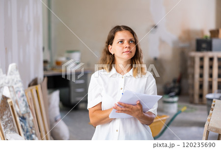 Woman designer checking documents during repair works Woman designer checking documents during repair works 120235690