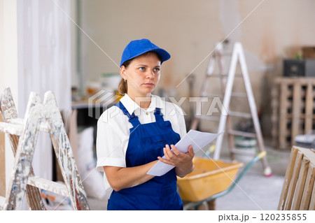 Woman foreman checks the completed construction work on drawing 120235855
