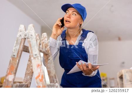 Young woman engineer in uniform is talking on a mobile phone Young woman engineer in uniform is talking on a mobile phone 120235917