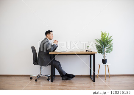 Asian businessman working on laptop in minimalist office setting Asian businessman working on laptop in minimalist office setting 120236183