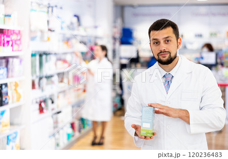 Portrait of man druggist in drugstore with drug package 120236483