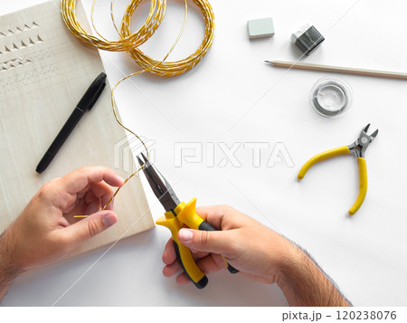 Hands crafting diy jewelry with wire and tools on white background Hands crafting diy jewelry with wire and tools on white background 120238076