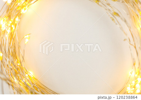 A bright gold-colored Christmas garland lies in a circle on a white background with space for text in the center. The concept of the holiday, Christmas and New Year. High quality photo 120238864