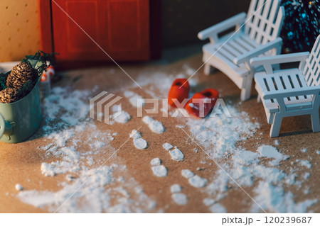 雪の足跡が残るミニチュアの冬の玄関シーン - 木製チェアと温かみのある小物たち 120239687