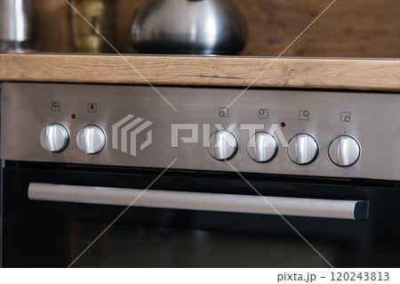 Control panel of an oven with silver knobs in a stylish kitchen. Control panel of an oven with silver knobs in a stylish kitchen. 120243813