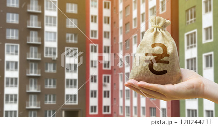 Ukrainian hryvnia bag against the background of modern high-rise buildings. Investing in the purchase of real estate. Affordable housing and mortgage rates. 120244211