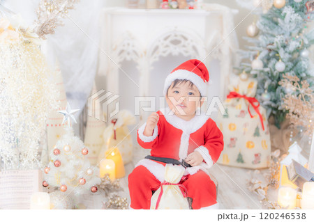 サンタの衣装を着てクリスマスツリーのフォトセットでご機嫌にはしゃぐ2歳の笑顔のこども サンタの衣装を着てクリスマスツリーのフォトセットでご機嫌にはしゃぐ2歳の笑顔のこども 120246538
