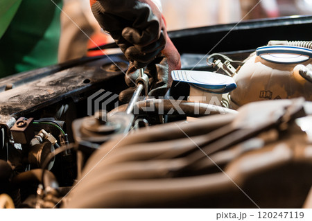 Mechanic Using Socket Wrench Underneath Car Hood for Engine Repair 120247119