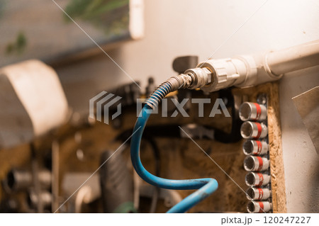 Air Compressor Hose Connected to Wall-Mounted Fittings in Garage Workspace 120247227
