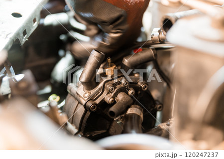 Close-Up of an Automotive Mechanic Working on a Car Engine's Water Pump 120247237