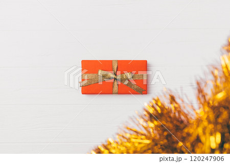 A small red box with gold ribbon sits on a white background A small red box with gold ribbon sits on a white background 120247906