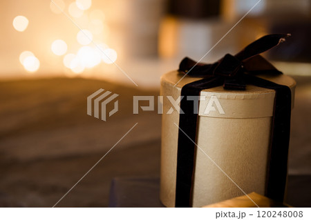 Elegant Gold Gift Box with Black Ribbon Surrounded by Soft Bokeh Lights Elegant Gold Gift Box with Black Ribbon Surrounded by Soft Bokeh Lights 120248008