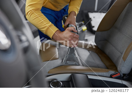 Man worker cleaning car interior with washing vacuum cleaner Man worker cleaning car interior with washing vacuum cleaner 120248177