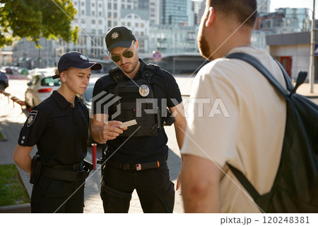 Patrol policeman and policewoman checking personal documents of citizen 120248381