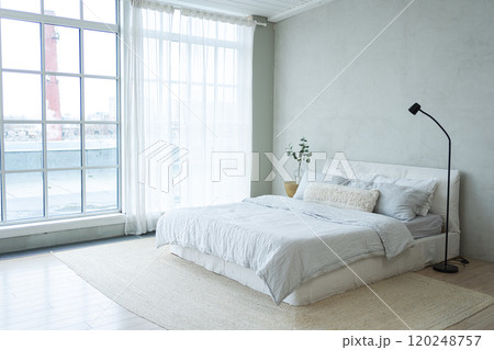 Stylish loft bedroom interior. Spacious design apartment with light walls large windows big bed. Clean modern decoration with elegant furniture in minimalist Scandinavian style Stylish loft bedroom interior. Spacious design apartment with light walls large windows big bed. Clean modern decoration with elegant furniture in minimalist Scandinavian style 120248757
