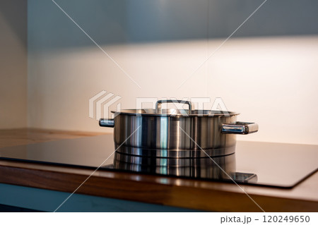 stainless steel pot on electronic modern flat stove in low light on counter kitchen room stainless steel pot on electronic modern flat stove in low light on counter kitchen room 120249650