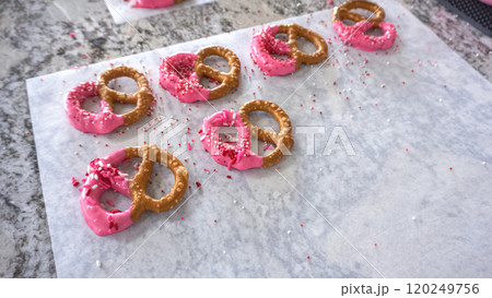 Freshly dipped and still glistening, these crunchy pretzels are lovingly adorned with pink chocolate and a scattering of colorful sprinkles, promising a feast for the senses. Freshly dipped and still glistening, these crunchy pretzels are lovingly adorned with pink chocolate and a scattering of colorful sprinkles, promising a feast for the senses. 120249756