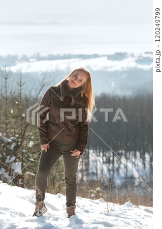 Full-length portrait of young woman on top of hill in winter. Model walking in winter nature. Vertical frame. 120249799