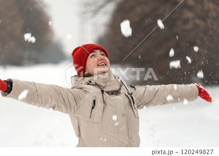 Happy young woman throwing snow in the air on a snowy winter day. Walking in winter park 120249827