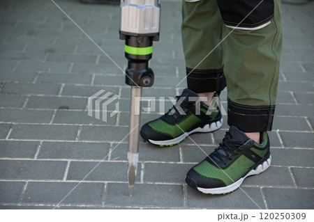 A hardworking Construction Worker equipped with a Demolition Tool working diligently on the Pavement 120250309