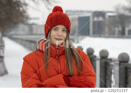 Portrait of a girl in a red knitted hat against the backdrop of a winter city 120251157