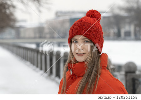 Portrait of a beautiful girl in a red jacket and a red hat in winter 120251158