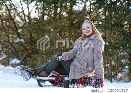 Beautiful woman wearing fur coat sitting on sleigh. Girl having fun on snowy winter day. Beautiful woman wearing fur coat sitting on sleigh. Girl having fun on snowy winter day. 120251337
